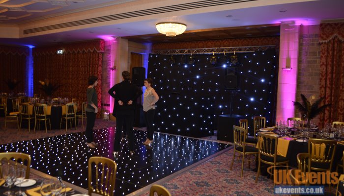 A black starlit dance floor with uplighters and star cloth backdrop for a birthday party