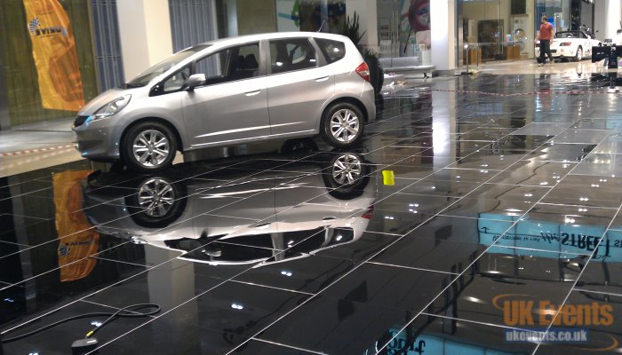 black exhibition flooring with cars parked on top of the sprung flooring