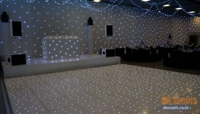 a white star cloth backdrop with white dj booth and sparkly dance floor